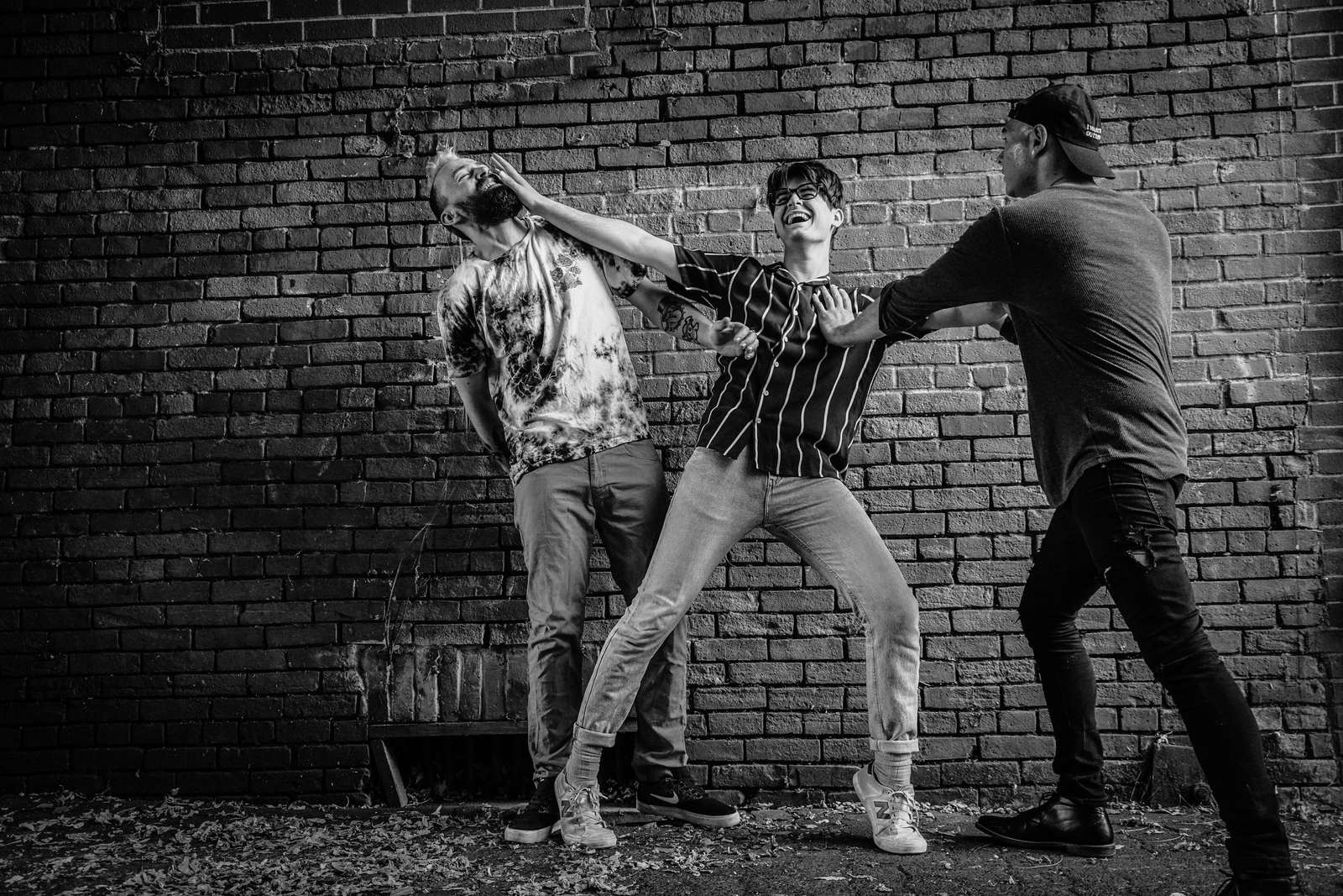Band clowning around against a brick wall, monochrome